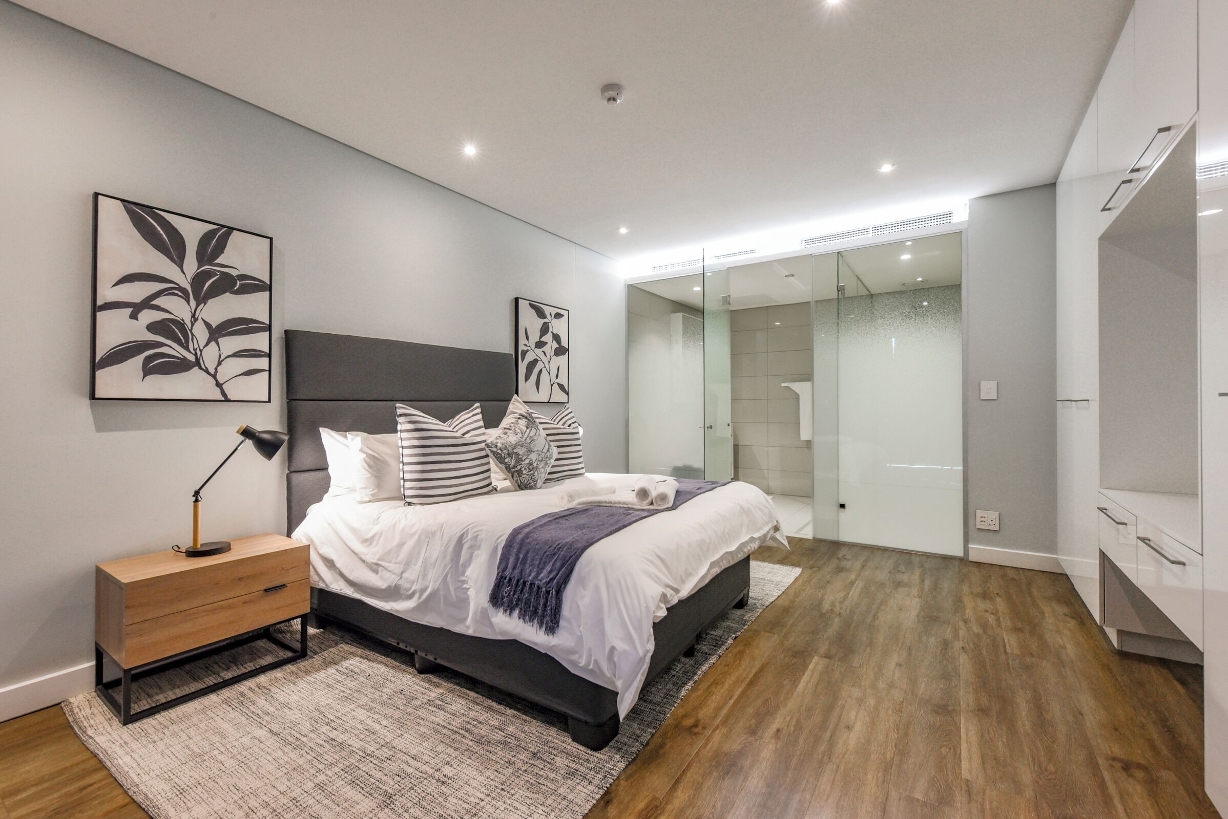 A modern bedroom with a bed, bedside table, and artwork on the wall.