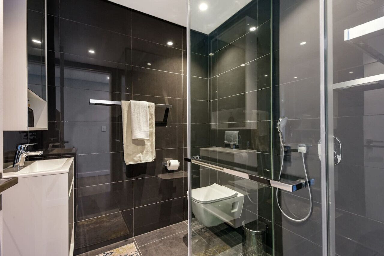 Un bagno moderno con doccia vetrata, un water e un lavandino.