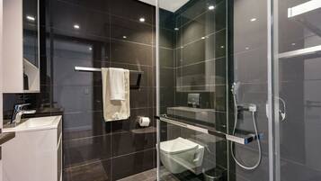 Un bagno moderno con doccia vetrata, un water e un lavandino.