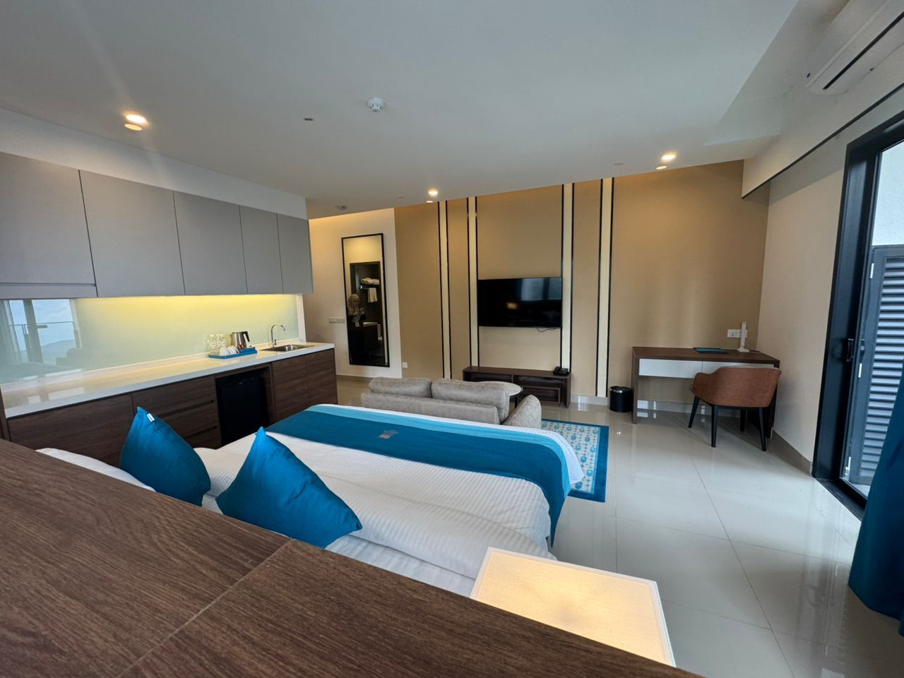 Une chambre d’hôtel moderne équipée d’un grand lit, d’un bureau, d’un canapé et d’une télévision.