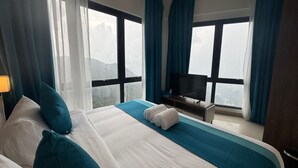 A hotel room with a large bed, a TV, and a view of the mountains. - HAYWOOD HILLTOP WELLNESS LIVING (Genting Highlands)