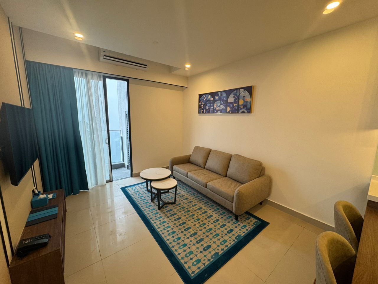 A living room with a sofa, a coffee table, a TV, and a painting on the wall.
