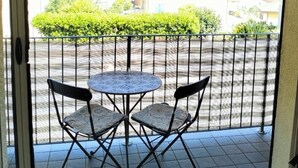 A balcony with a striped awning, two chairs, and a small table. - Double room with private bathroom "Chez Nous" (La Spezia)