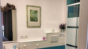 A modern bathroom with a bidet, toilet, and sink. There is a framed picture on the wall and a small plant on the counter. - Double room with private bathroom "Chez Nous" (La Spezia)