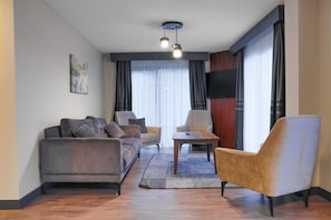 A modern living room with a sofa, armchair, and coffee table, a flat-screen TV mounted on the wall, and a large window with curtains. - Best Western Plus Sapanca (Sapanca)