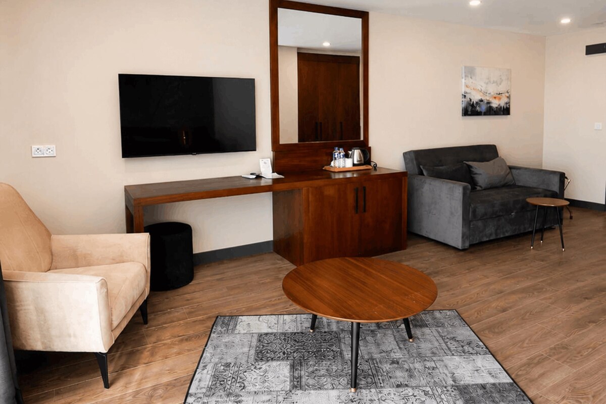 A modern living room with a sofa, a chair, a coffee table, a TV, a cabinet, and a mirror.