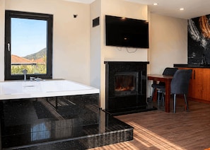 A modern bathroom with a large bathtub, a fireplace, and a dining area with a table and chairs. - Best Western Plus Sapanca (Sapanca)