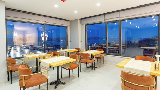 Un espace de restauration moderne, doté de tables et de chaises, de grandes fenêtres offrant une vue sur la ville, et d’un design épuré et contemporain.