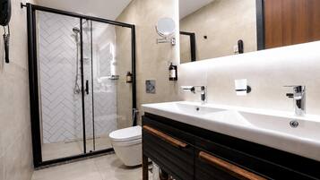 Ein modernes Badezimmer mit einer Duschkabine aus Glas, einem weißen Waschbecken mit Chromarmaturen und einem Holz-Waschtisch.