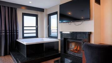 A modern living room with a fireplace, a flat-screen TV mounted above it, and a window with curtains.