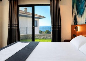 A hotel room with a bed, a view of a building through a glass door, and a nightstand with a lamp. - Best Western Plus Sapanca (Sapanca)