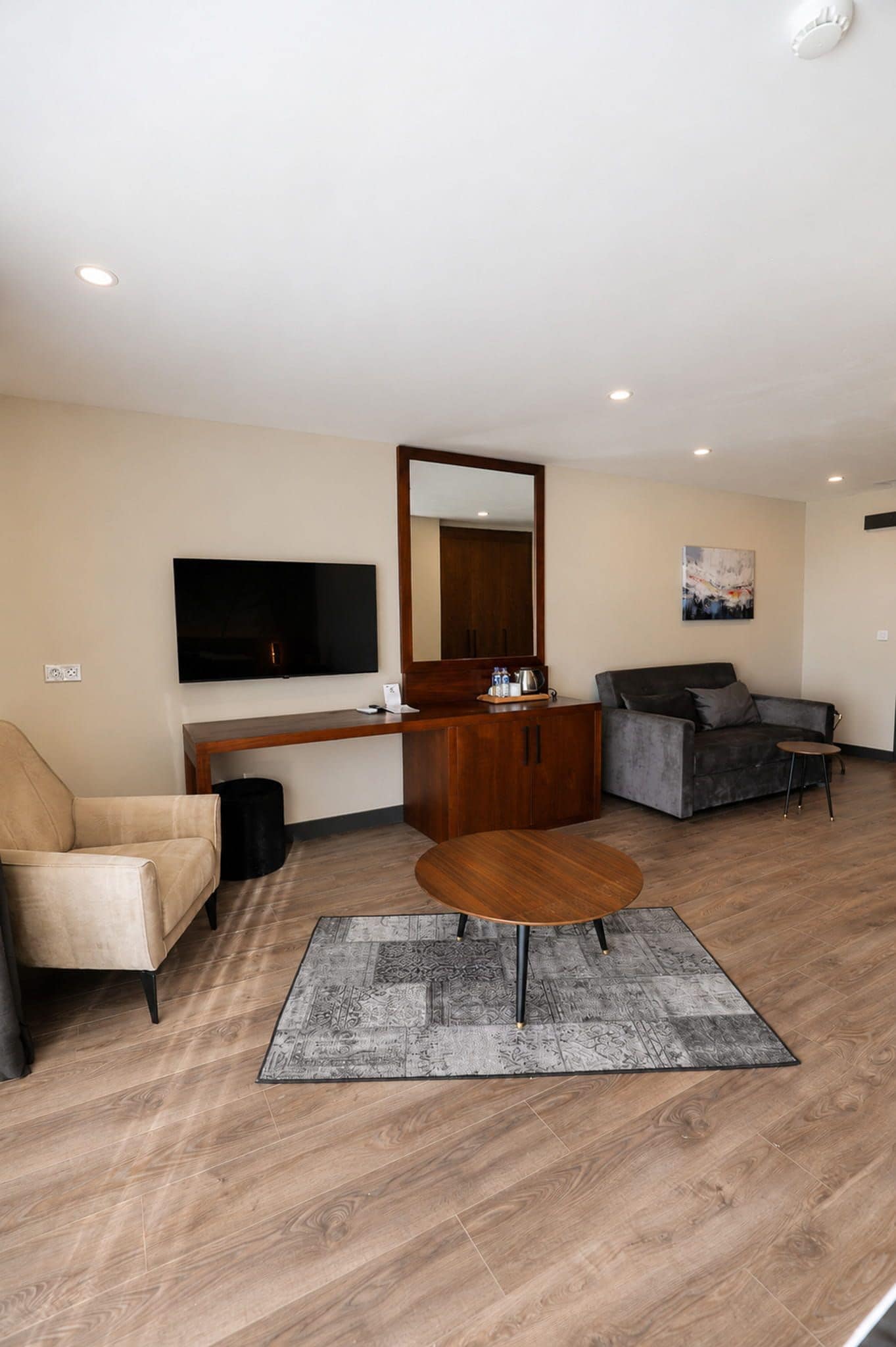 Una sala de estar moderna con un televisor de pantalla plana, un sofá, una mesa de centro y un aparador de madera.