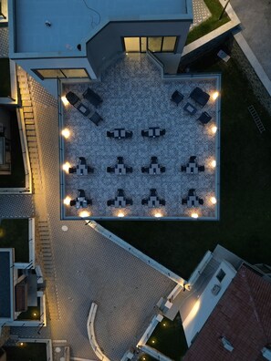 An aerial view of a courtyard with a tiled floor, surrounded by buildings. There are multiple tables and chairs arranged for outdoor dining. - Best Western Plus Sapanca (Sapanca)