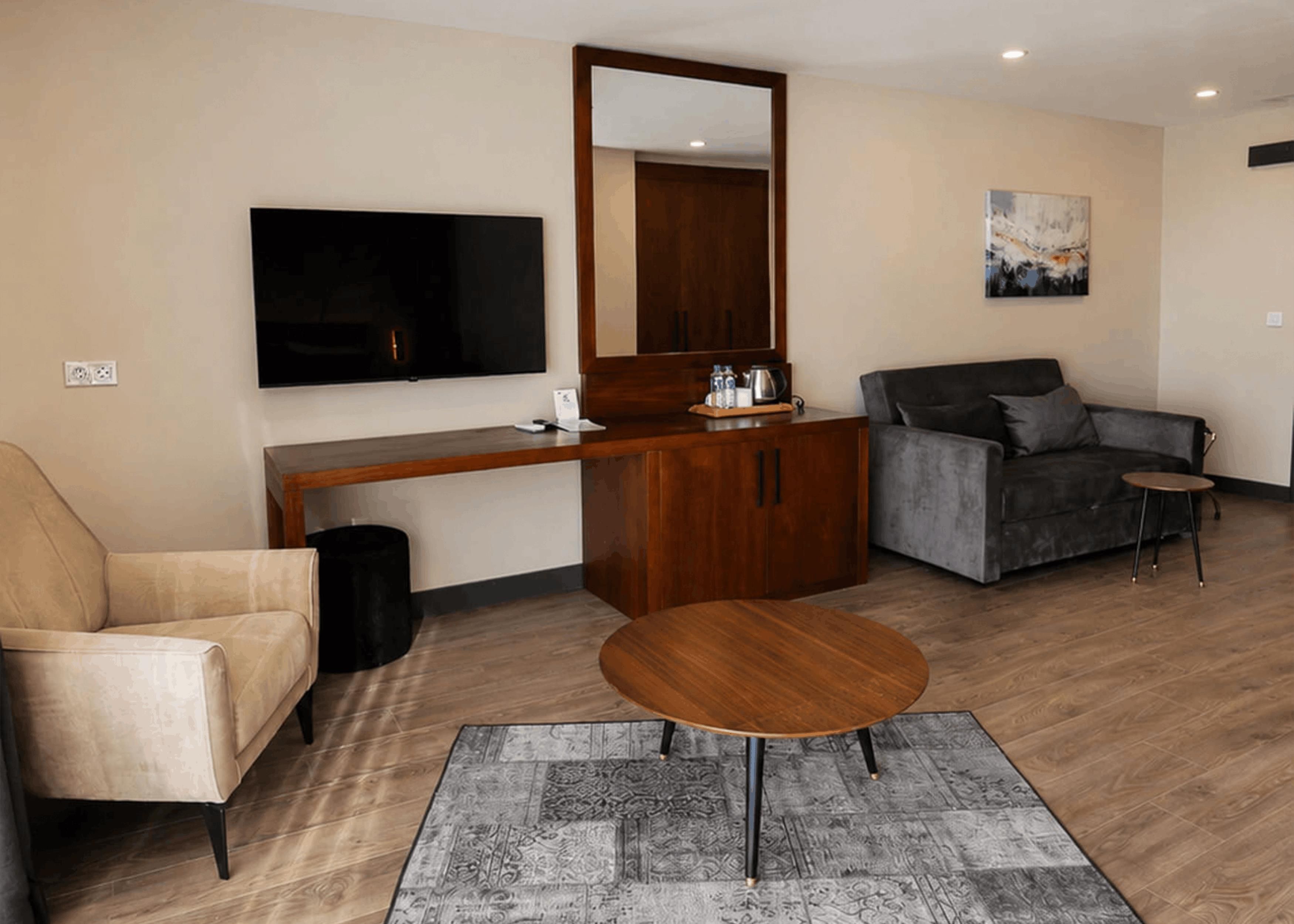 A modern living room with a sofa, a coffee table, a TV, a wooden cabinet, and a painting on the wall.