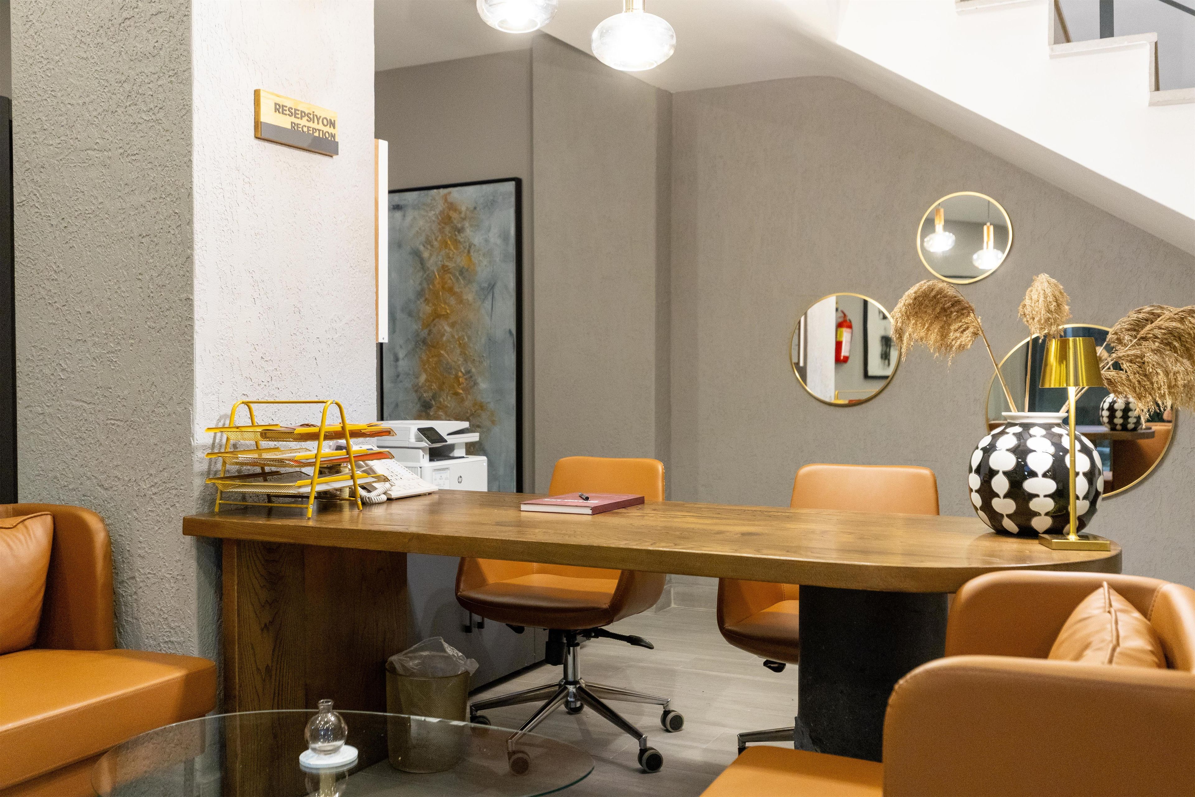 Una sala de conferencias moderna con una mesa de madera, sillas naranjas y un cartel de recepción.