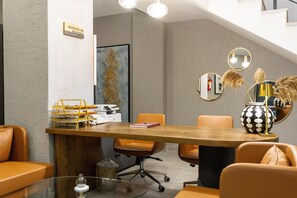 Een moderne vergaderruimte met een houten tafel, oranje stoelen en een receptiebord.
