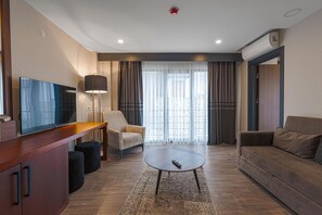 A modern living room with a flat-screen TV, a sofa, a coffee table, and a chair. - Best Western Plus Sapanca (Sapanca)