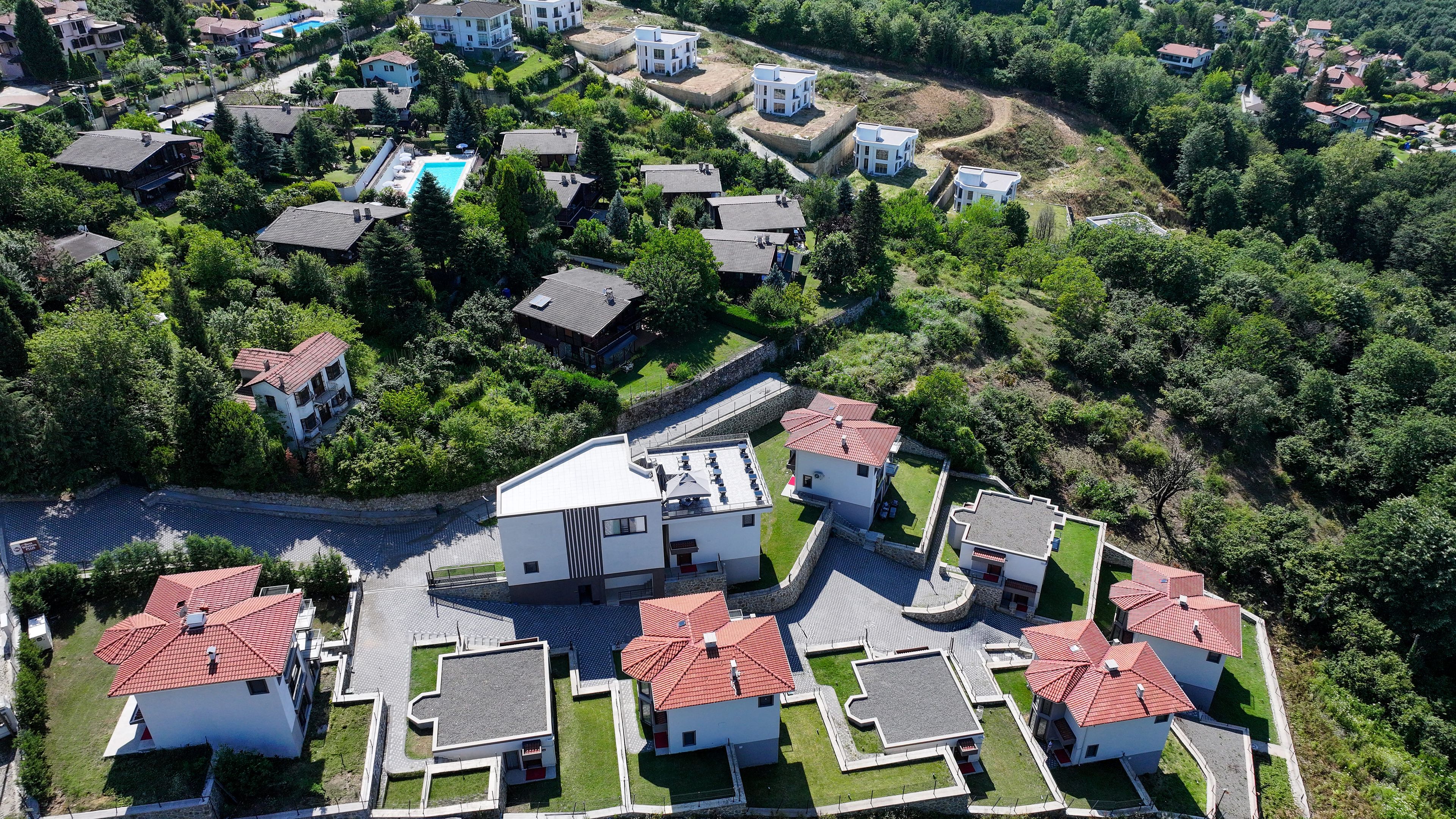 Vista aérea de una zona residencial con casas, una piscina y áreas verdes.