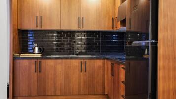 A kitchen with wooden cabinets, a black tiled backsplash, and stainless steel appliances.