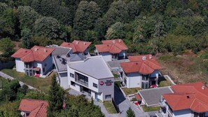 Egy lakóövezet, melyben modern házak találhatók, piros cseréptetőkkel, és egy központi épület, melyen tábla van.