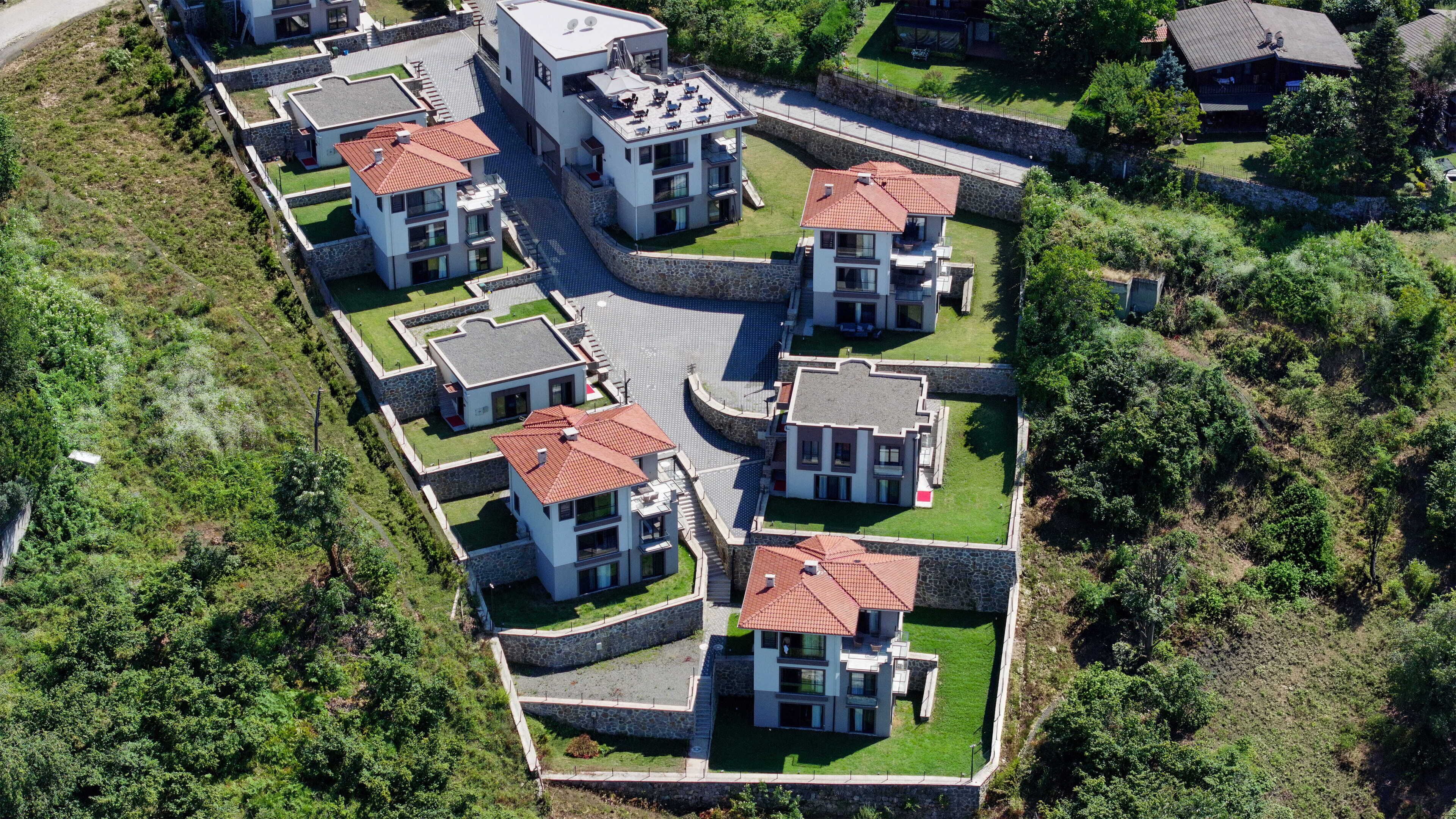 Zona residencial con casas modernas, muros de piedra y un espacio pavimentado en el centro.