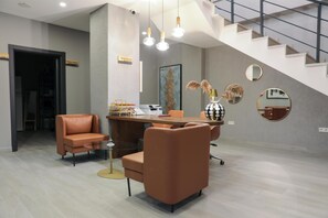 A modern reception area with a desk, two leather chairs, a coffee table, and a staircase. - Best Western Plus Sapanca (Sapanca)