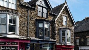 A traditional stone building with multiple windows and a shop on the ground floor. - Lake Road Apartments (Bowness-on-Windermere)