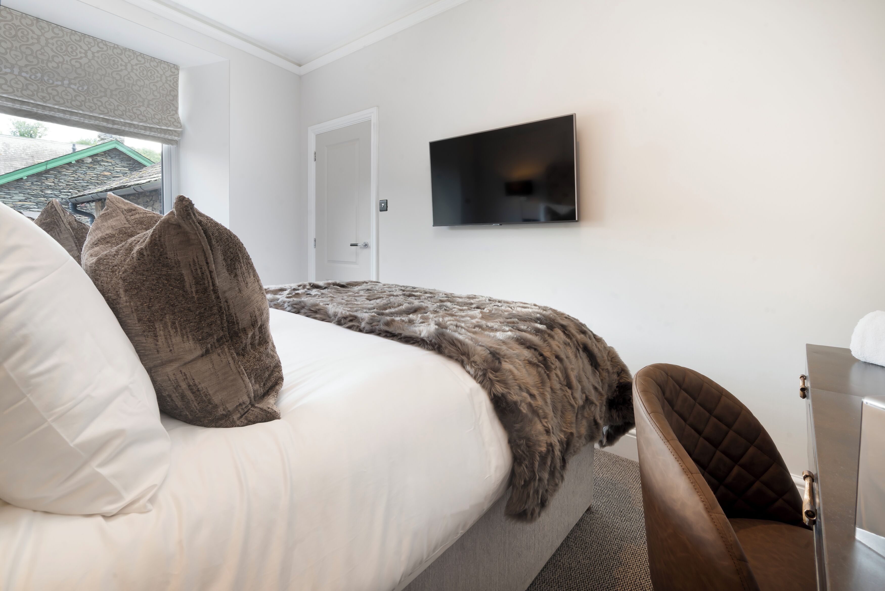 Un dormitorio con cama, televisor en la pared y una puerta.