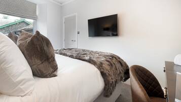 Un dormitorio con cama, televisor en la pared y una puerta.