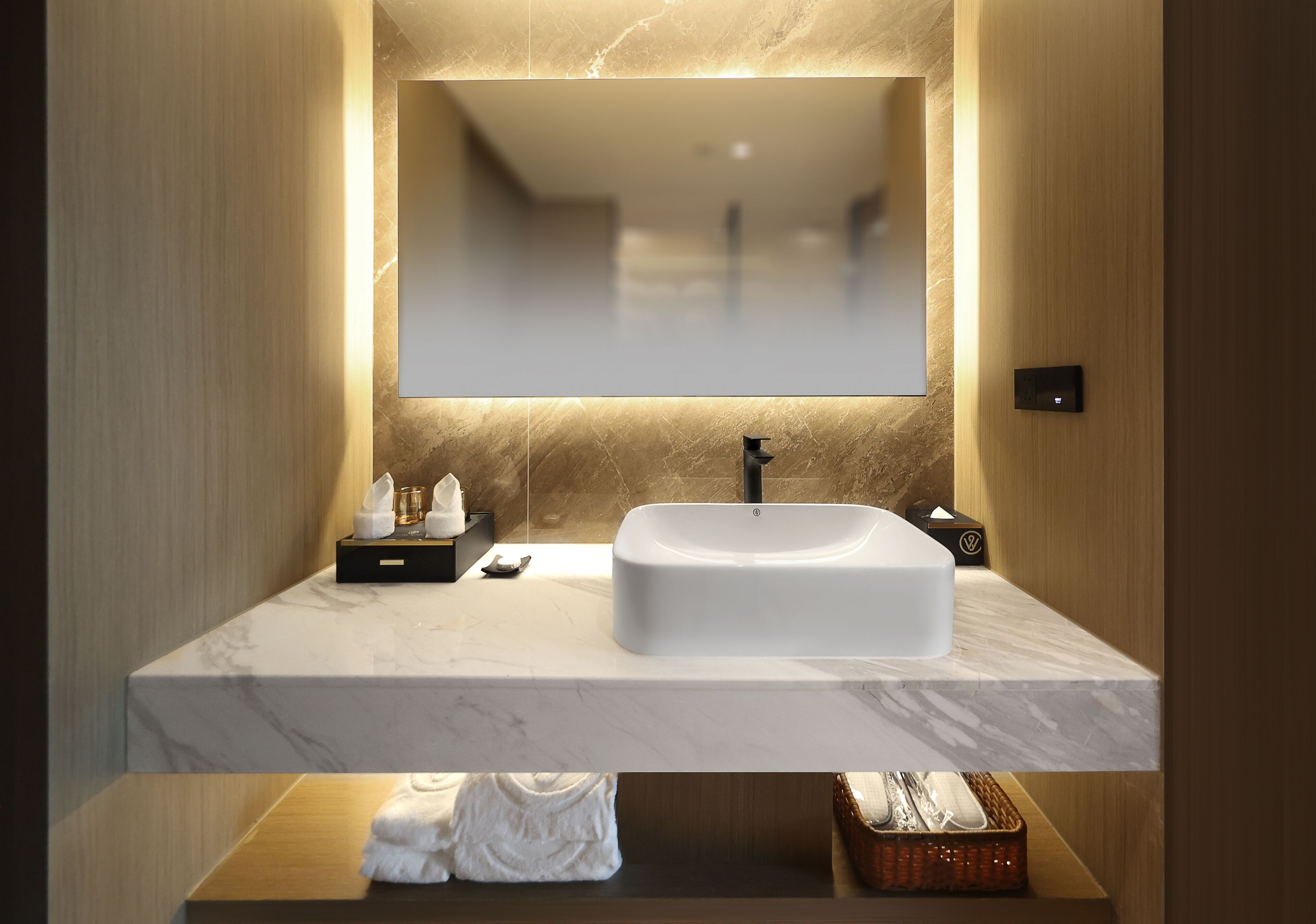 A modern bathroom with a marble vanity, a large mirror, and a built-in sink.