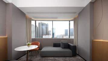 Habitación de hotel moderna con vista a la ciudad, una pequeña mesa redonda, un sofá y piso alfombrado.