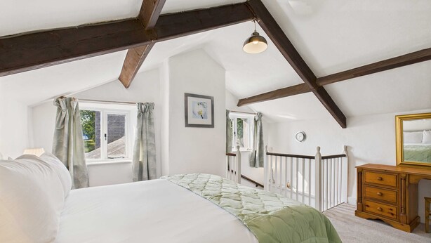 A bedroom with a bed, a dresser, a window, and a ceiling with exposed beams. - Host Stay Brackenrigg Cottage (Morpeth)