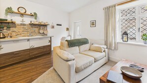 A cozy living room with a sofa, a coffee table, and a window with a view. - Host Stay Brackenrigg Cottage (Morpeth)