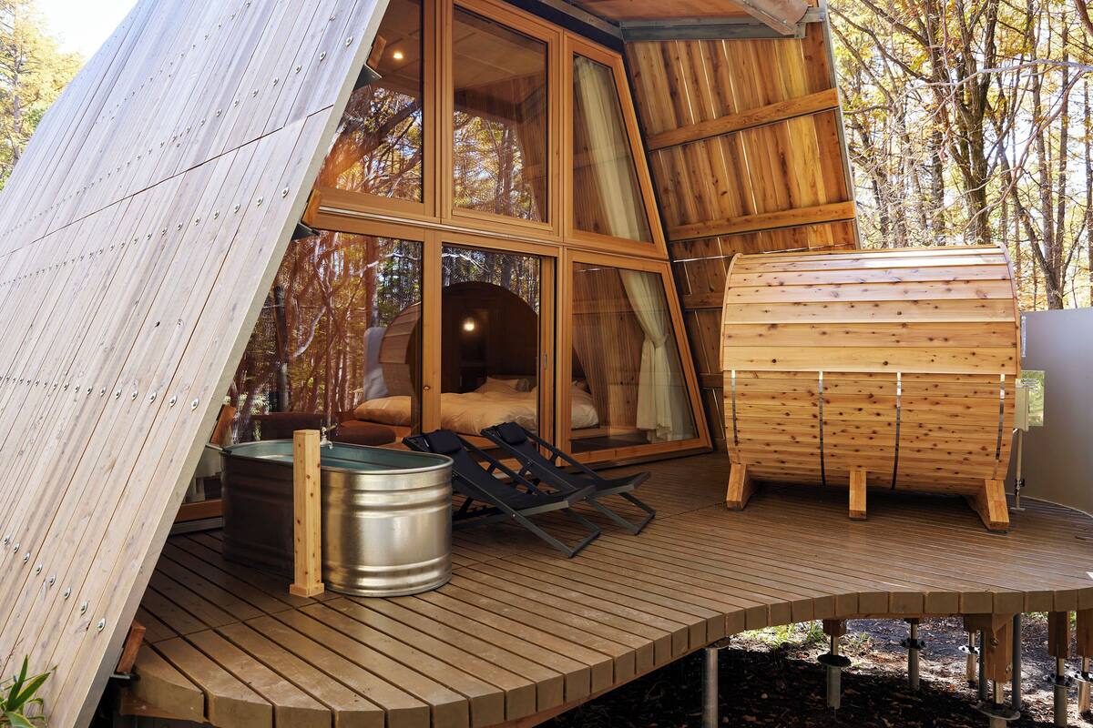 Eine Holzterrasse mit Sauna, Whirlpool und Liegestühlen.