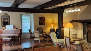 A cozy living room with a wooden dining table, comfortable chairs, a fireplace, and a piano. - La Frigoule, a gîte in the heart of the Cévennes Park (Saint-Sébastien-d'Aigrefeuille)