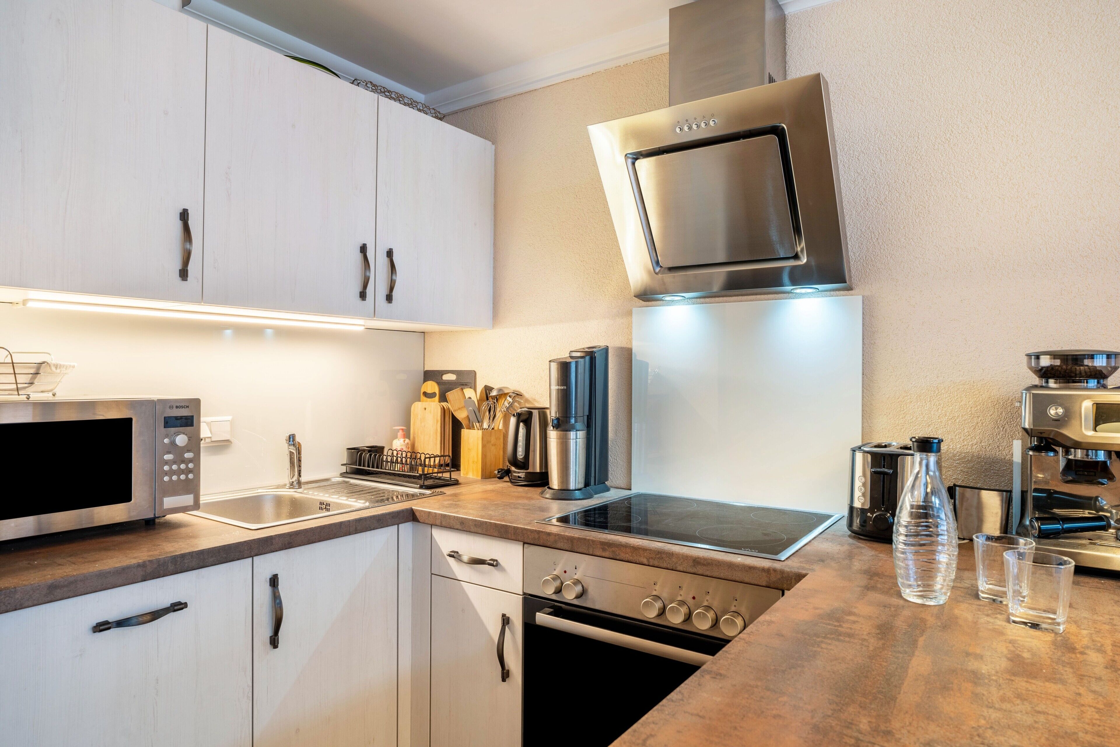 A modern kitchen with a built-in microwave, oven, and coffee machine.