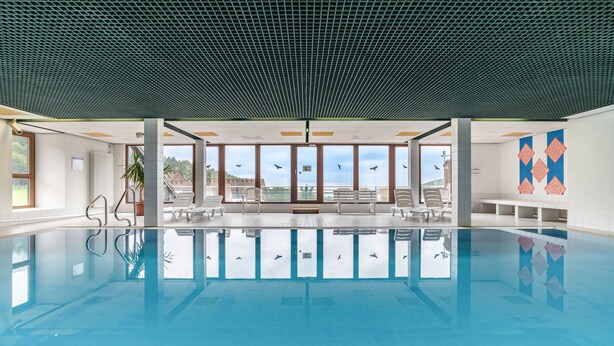 A swimming pool with clear water, surrounded by lounge chairs and a view of the sky.