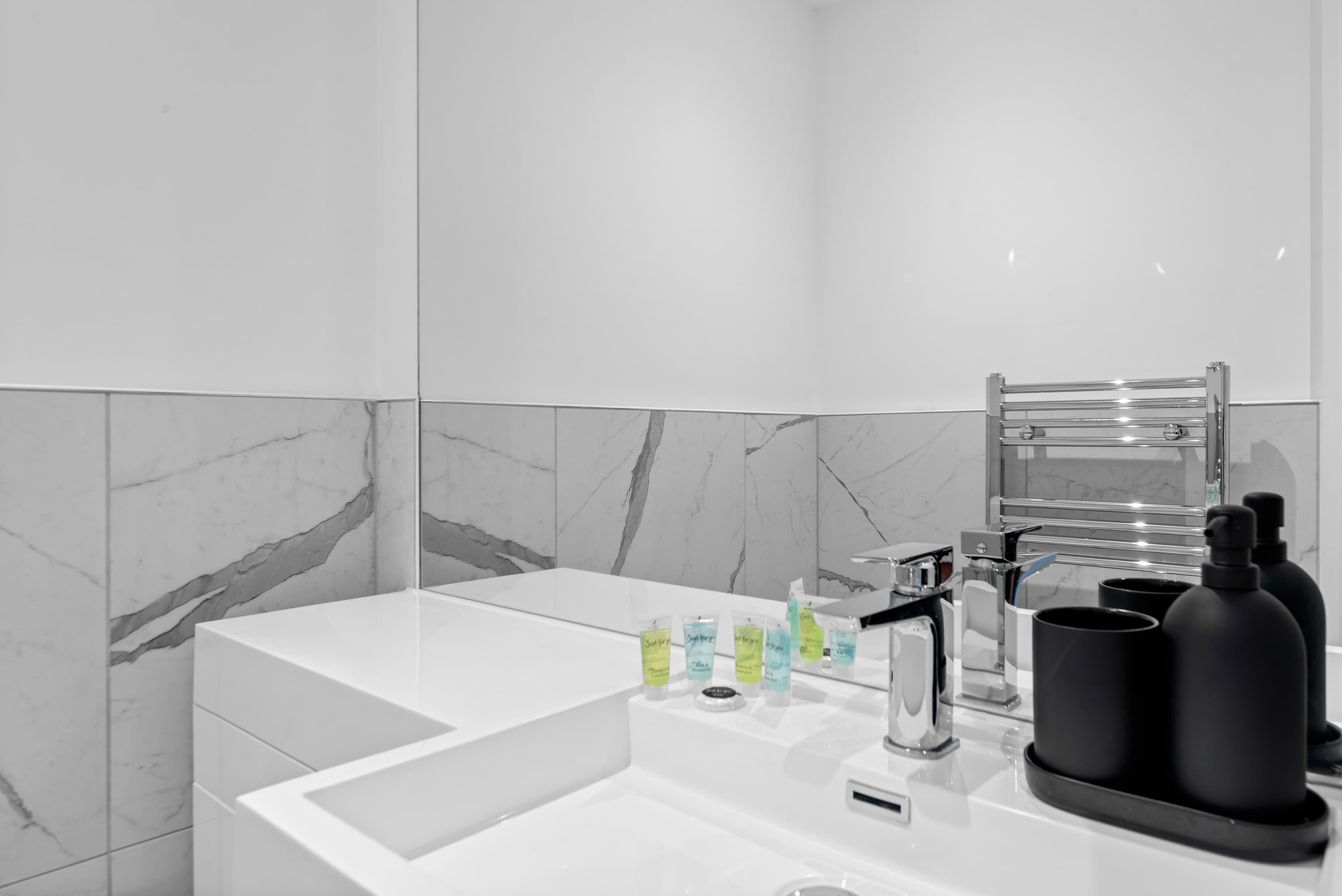A modern bathroom with a white sink, a mirror, and toiletries.