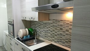 Una cuina moderna amb un obrador d'acer inoxidable, un rentaplats i un forn integrat.