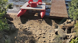 Un entorno junto al lago con un muelle de madera y una mesa con sillas rojas.