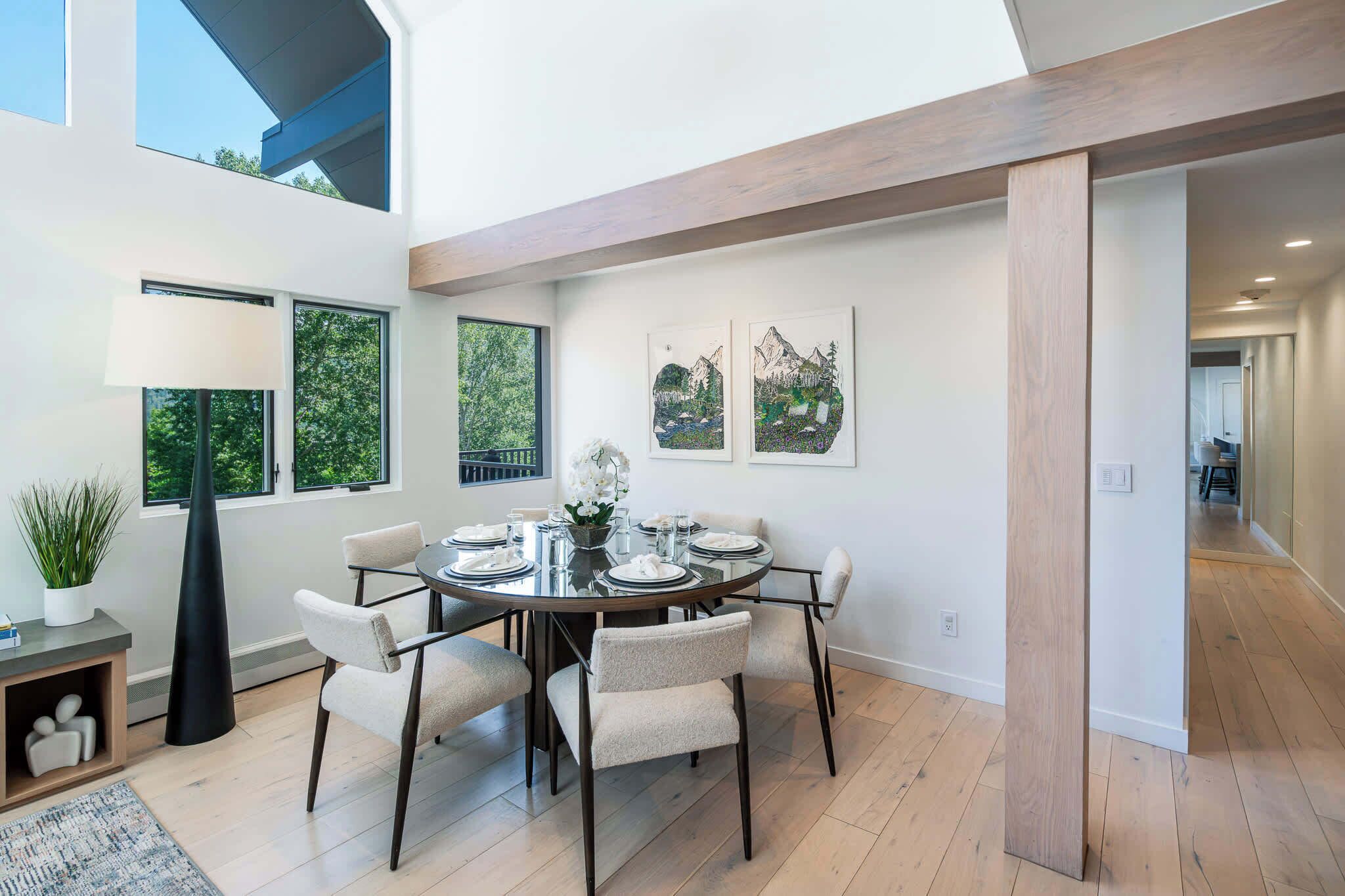 Une salle à manger moderne avec une table ronde, six chaises et des œuvres d’art accrochées aux murs.