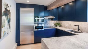 A modern kitchen with dark blue cabinets, stainless steel appliances, and a marble countertop. - Ski-in/Out 3BR w Central AC, Views, Pool & Hot Tub (Aspen)