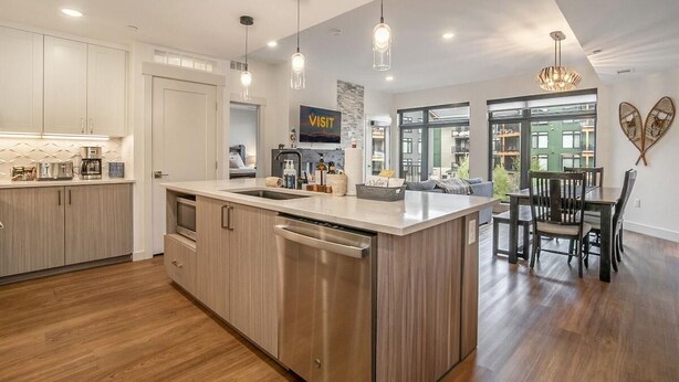 A modern kitchen with a central island, pendant lighting, and a dining area with a view. - TimberFox 3209 | 2BR Downtown, Hot Tub, A/C (Winter Park)