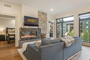 A modern living room with a fireplace, a sofa, and a large window.