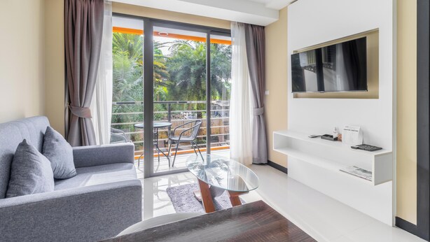 A modern living room with a grey sofa, glass coffee table, and a TV mounted on the wall. - Condo Gym Plane Views Near Beach C172 (Mai Khao)