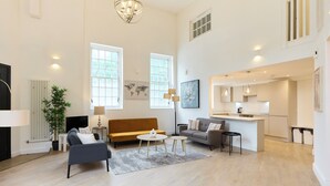 A spacious living area with a sofa, coffee table, and a dining area with a kitchen. - Central Tadworth Flat (Tadworth)