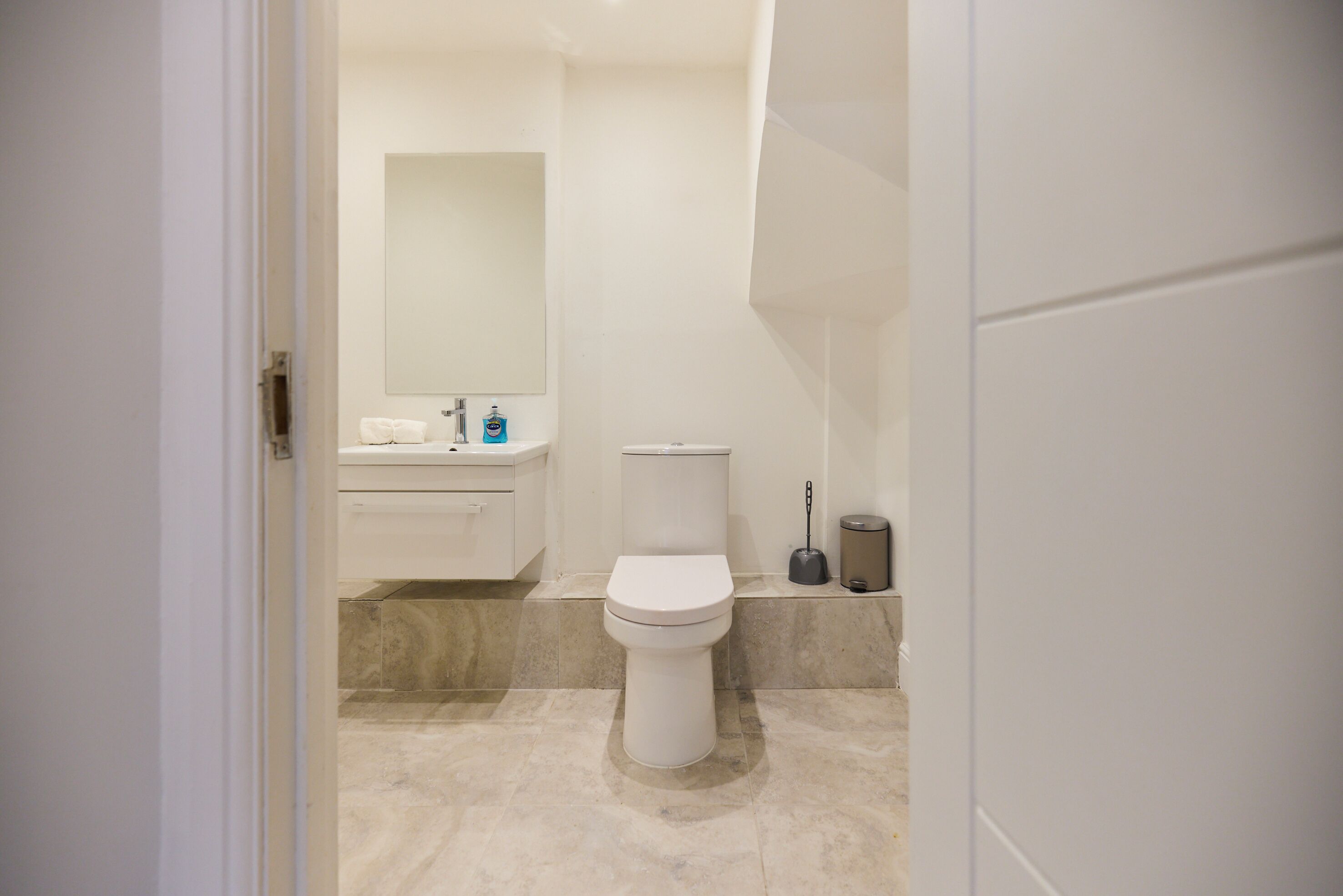 A bathroom with a toilet, sink, and mirror.
