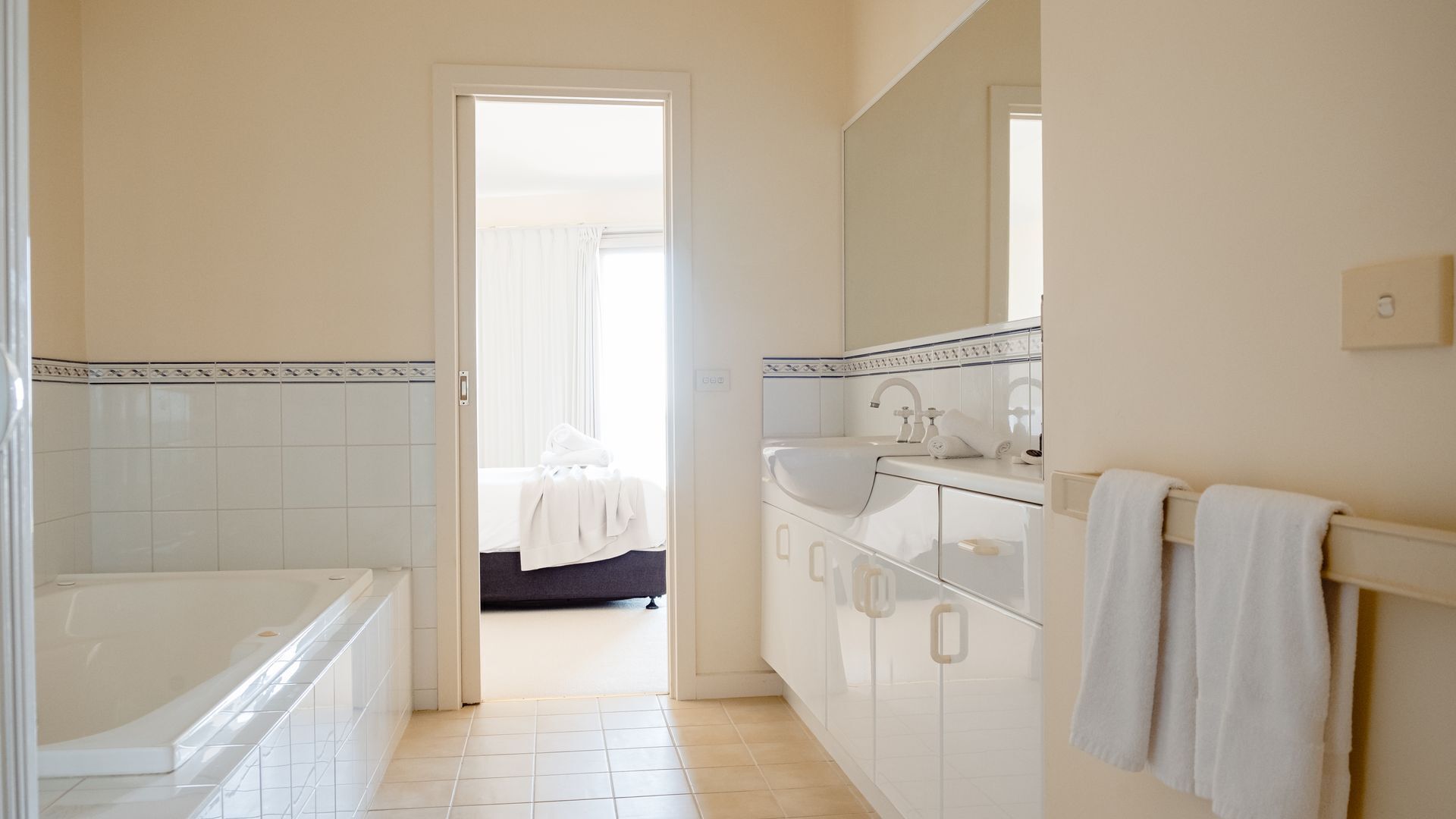 A hotel bathroom with a bathtub, a sink, and a mirror.