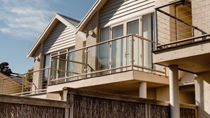 A modern building with a balcony, large windows, and a wooden fence. - Sandy Nook - 2/192B Griffiths Street (Port Fairy)