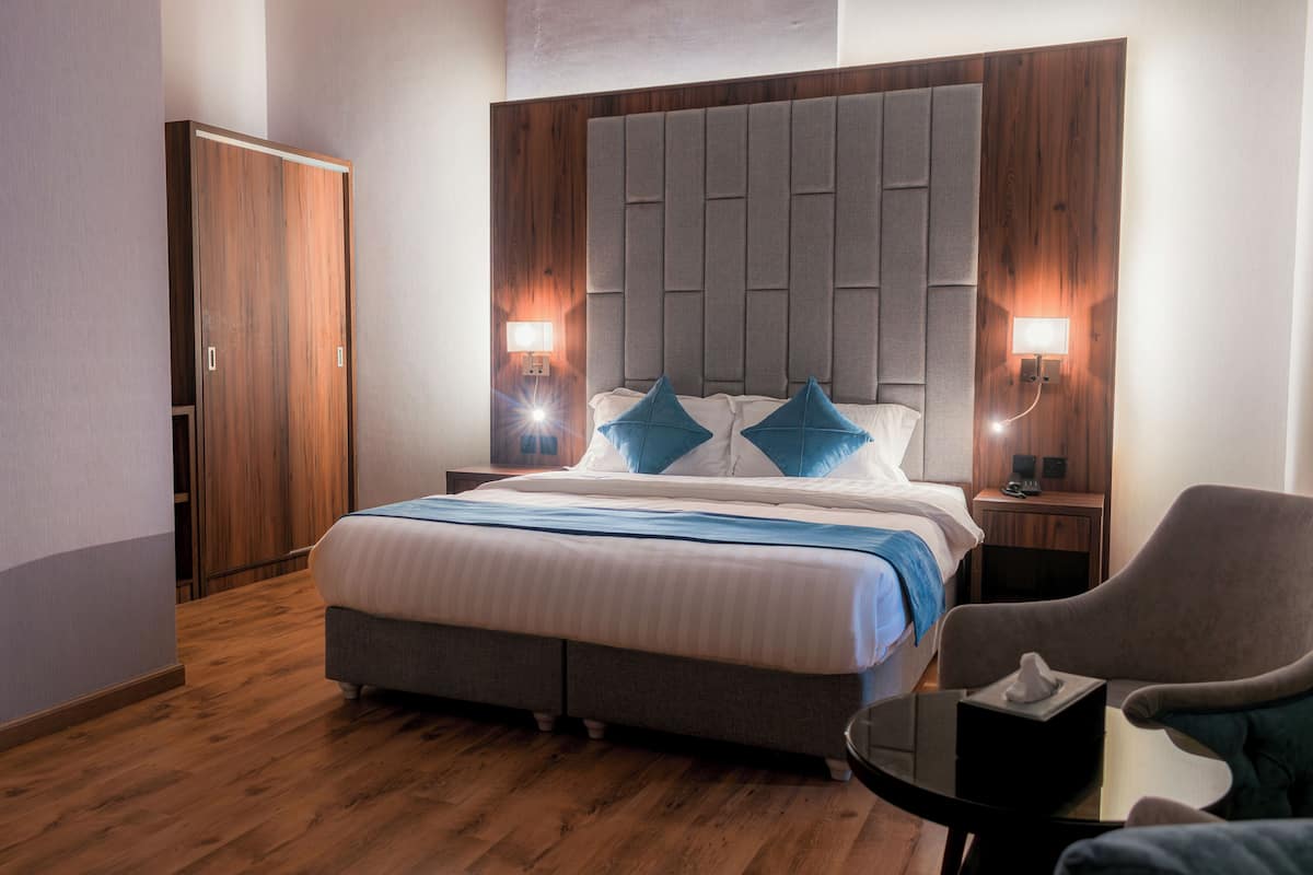 Ein Schlafzimmer mit einem großen Bett, einem Holzschrank, zwei Nachttischlampen und einem Sessel.